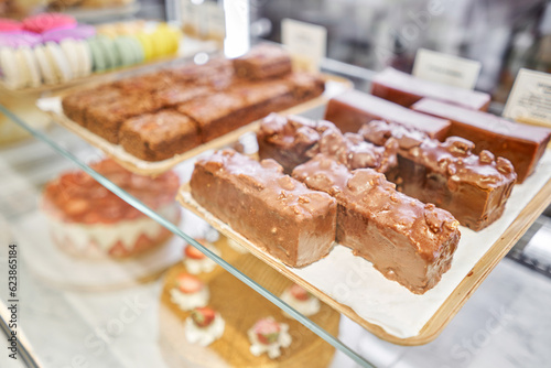 A variety of cakes covered with chocolate and decorated with pistachio mousse. A showcase in a pastry shop with delicious desserts with fresh berries and cream. Delicious pastries in the coffee shop.