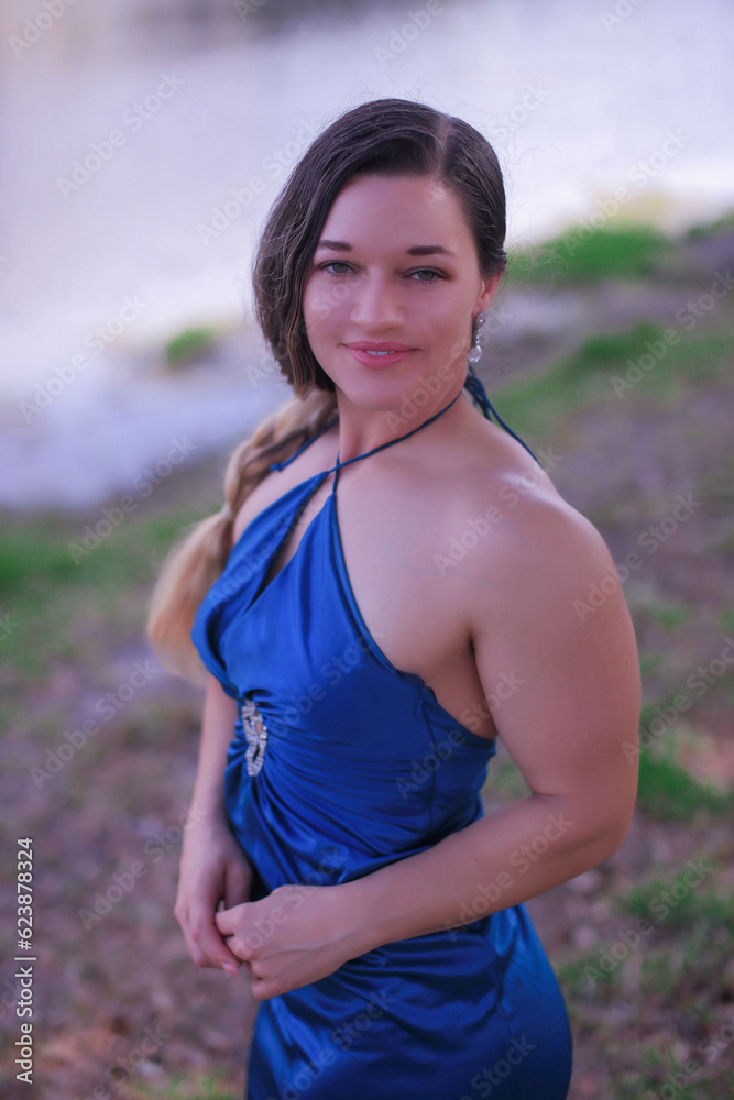 a beautiful big athlete fitness girl in a green dress poses on the street of America, in summer and smiles a beautiful big athlete fitness girl in a green dress poses on the street of America, in summer and smiles