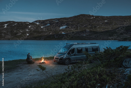 Frau an einem Lagerfeuer mit ihrem Camper Van 