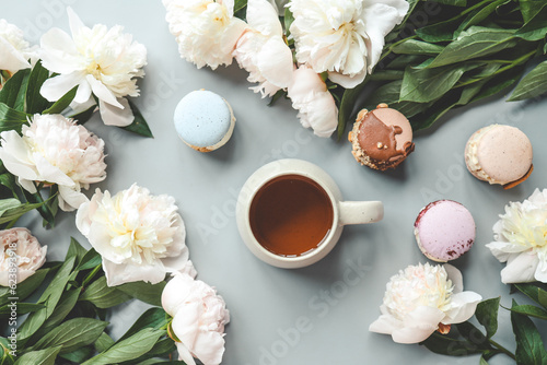 Cup of tea, macaroons and peonies, flat lay top view. good morning concept