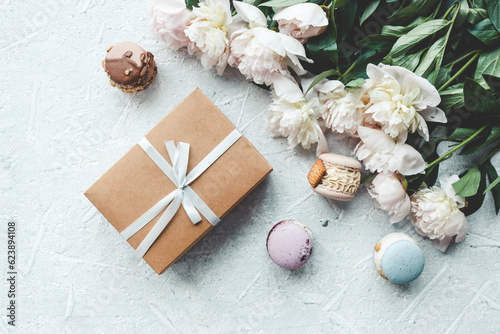 Gift box with bow, white peonies and sweet macaroons, holiday concept