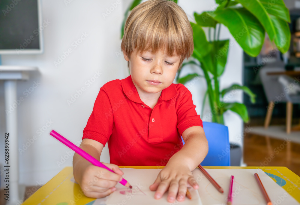 Back to school. Portrait of little child boy writing, drawing in notebook sitting at desk and doing homework. Pupil of primary school in class writing and reading. Home schooling and education at home Back to school. Portrait of little child boy writing, drawing in notebook sitting at desk and doing homework. Pupil of primary school in class writing and reading. Home schooling and education at home