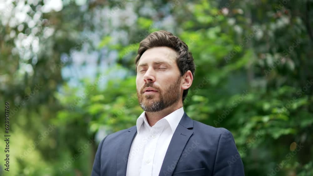 Happy handsome businessman relax, rests take a deep breath fresh air while standing in nature among trees in park square or forest Business man in formal suit enjoying with closed eyes outdoor outside Happy handsome businessman relax, rests take a deep breath fresh air while standing in nature among trees in park square or forest Business man in formal suit enjoying with closed eyes outdoor outside