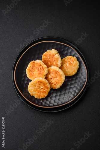 Delicious fresh cottage cheesecakes with raisins and vanilla on a black ceramic plate