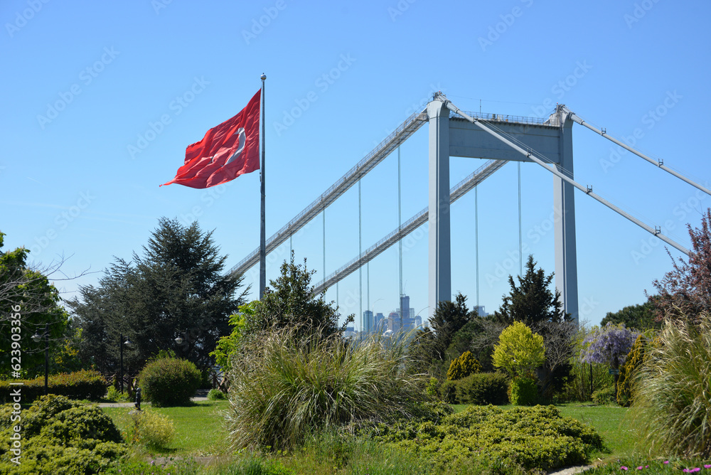 The Turkish flag is waving in the wind in a park overlooking the bridge over the Bosphorus and beautifully blooming sakura. Travel Istanbul background photo