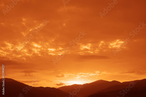 A bright colorful sunset sky over the black silhouettes of the mountains. Dark sunset sky with bright colors over a mountain. Scenic View Of Silhouette Mountains Against Sky During Sunset © Maxim Chuev