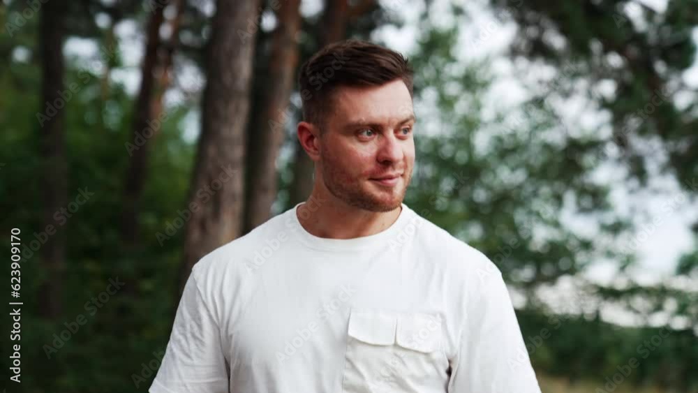 Caucasian unshaved man in white t-shirt walks in the nature. Relaxed man portrait spending time outdoors in summer. Caucasian unshaved man in white t-shirt walks in the nature. Relaxed man portrait spending time outdoors in summer.