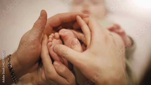Baby feet in mother and father hands. Tiny Newborn Baby's feet on female and male hands close up. Mom, Dad and his Child. Happy Family concept. Beautiful conceptual video of Maternity and Fatherhood