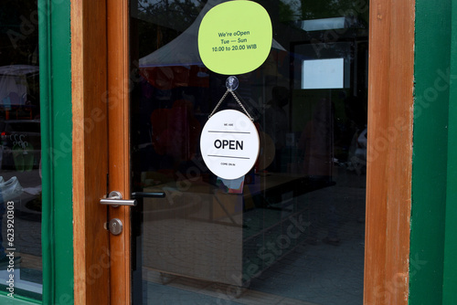 Open sign board hanging on the glass door of cafe, coffee shop, store or restaurant.