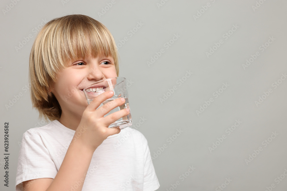 Happy little boy drinking fresh water on light grey background. Space for text Happy little boy drinking fresh water on light grey background. Space for text
