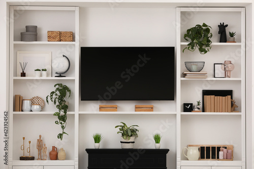 Modern TV set and shelves with decor near white wall. Interior design © New Africa