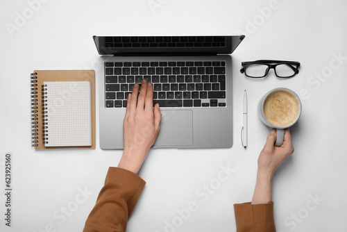 Woman using laptop at white table, top view