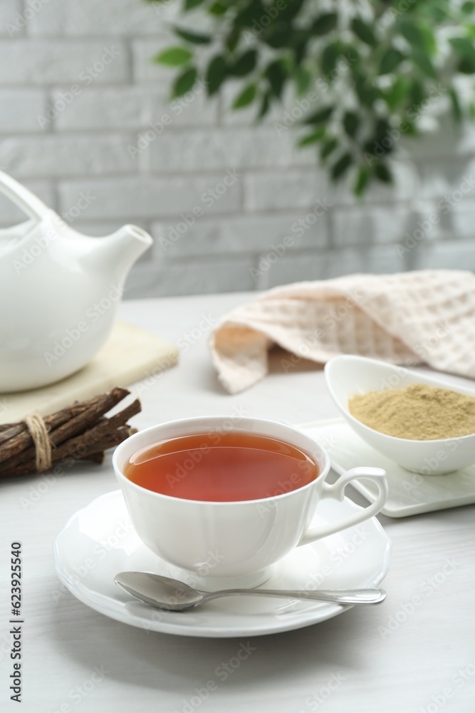 Aromatic licorice tea in cup served on white table Aromatic licorice tea in cup served on white table