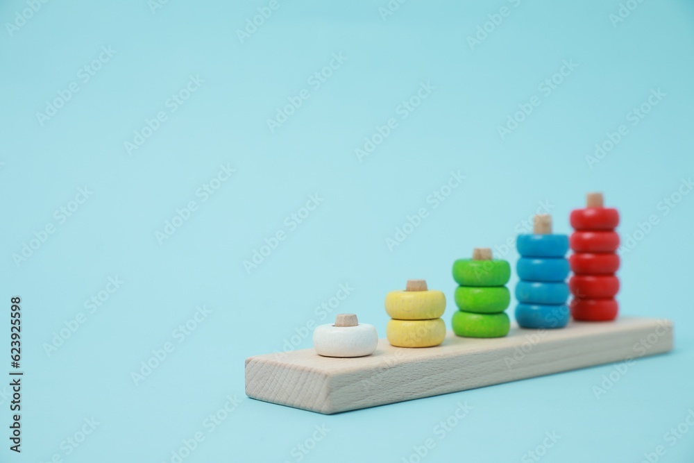Stacking and counting game wooden pieces on light blue background, space for text. Educational toy for motor skills development Stacking and counting game wooden pieces on light blue background, space for text. Educational toy for motor skills development