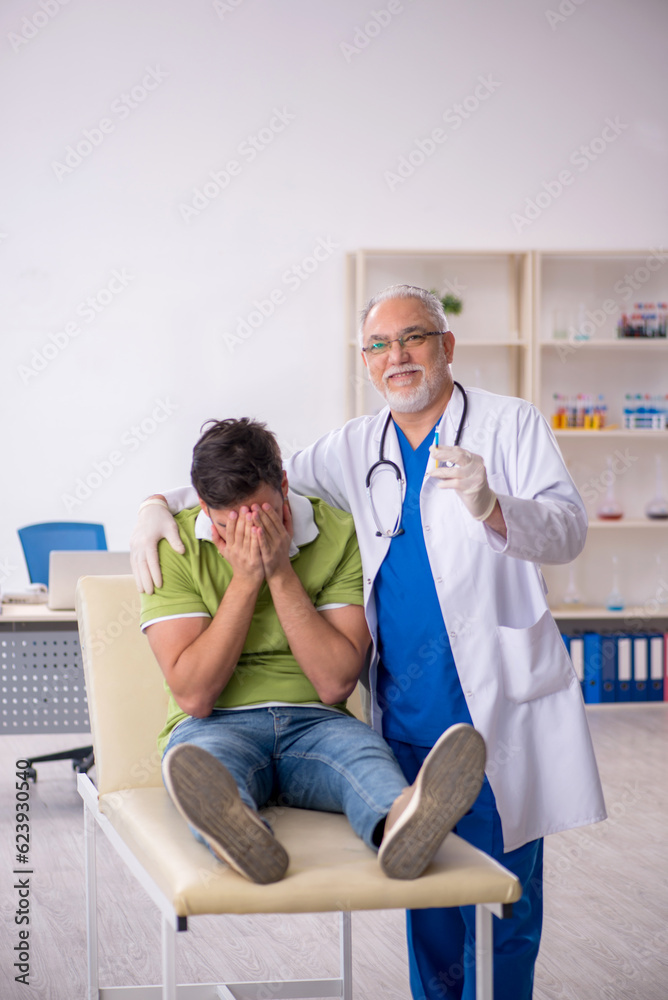 Obraz premium Young male patient visiting old male doctor in vaccination conce