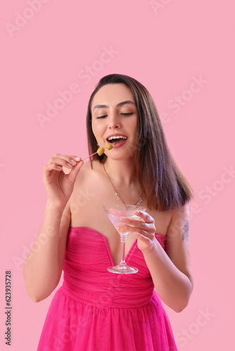 Beautiful woman with martini and olives on pink background