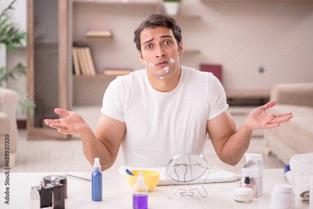 Young man shaving face at home
