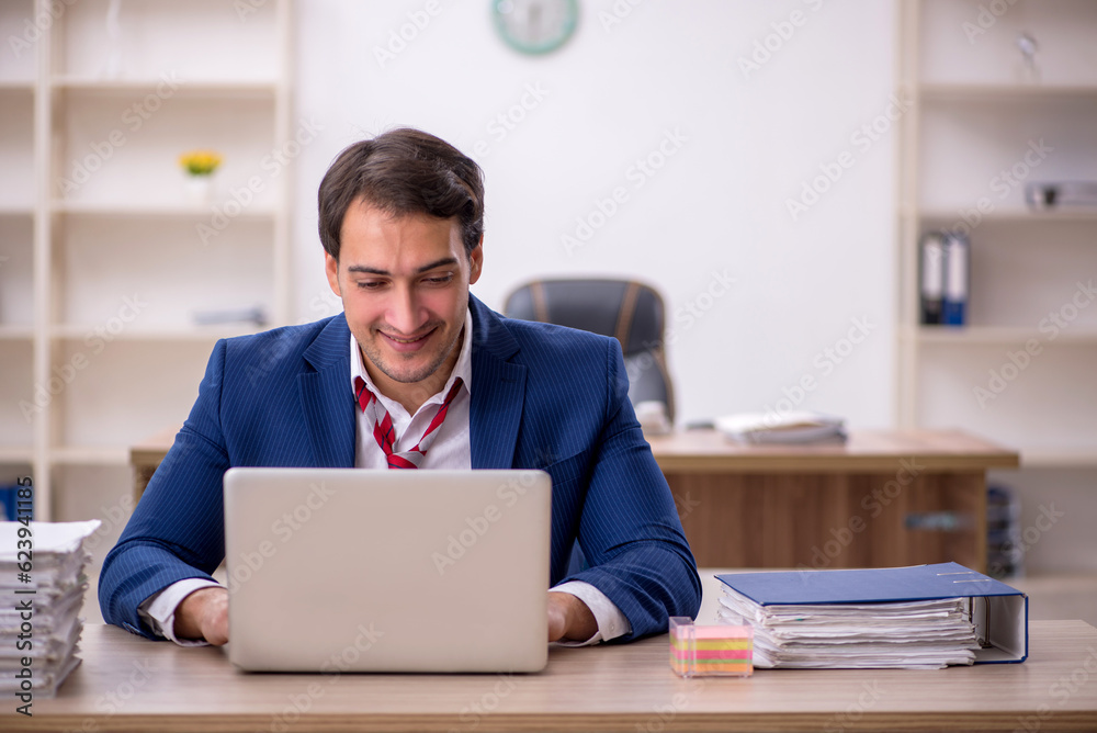 Young male employee and too much work in the office Young male employee and too much work in the office