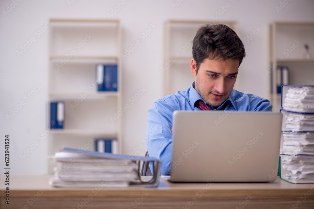 Young male employee and too much work in the office Young male employee and too much work in the office