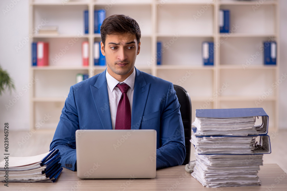 Young male employee and too much work in the office Young male employee and too much work in the office