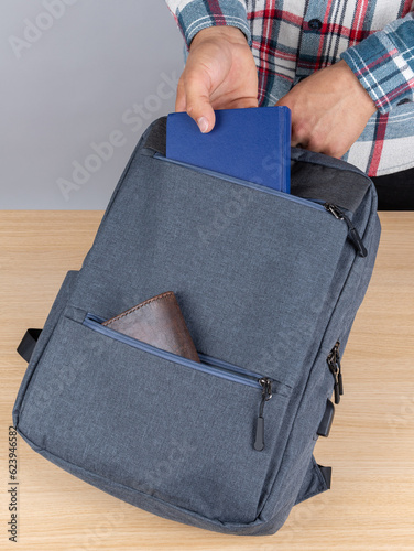 Close-up of a young male student taking out a book,notebook  from a backpack. photo