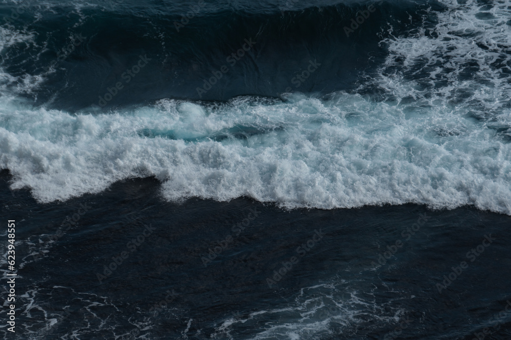 The waves of the ocean water meet with underwater pointed rocks