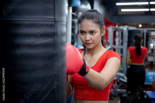 Determination of young asian woman having motivation boxing in fitness gym, active sport and workout, training boxing with strength and confidence, health and wellness, exercise and punch with cardio.