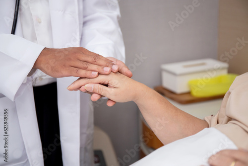 Closeup hands of doctor man encourage with elderly patient at the hospital, physician take care and holding hands for consoling senior sick, diagnostic disease and illness, medical concept.