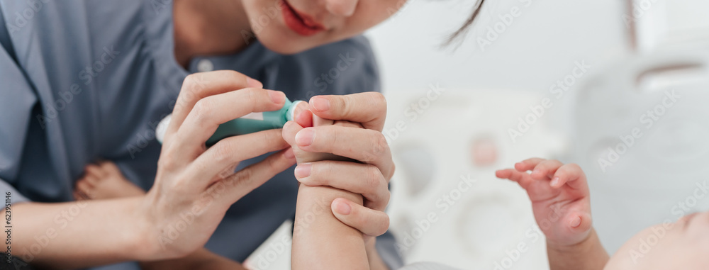 Fototapeta premium Closeup of Mother's Hand Expertly Using Specific Tool to Cutting and Filing Baby's Nails, Ensuring Hygiene and Health. Selective Focus.