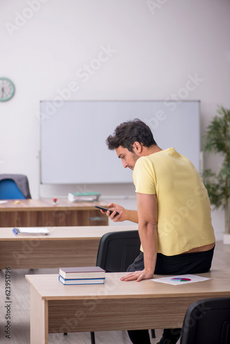 Young male student teacher sitting in the classroom
