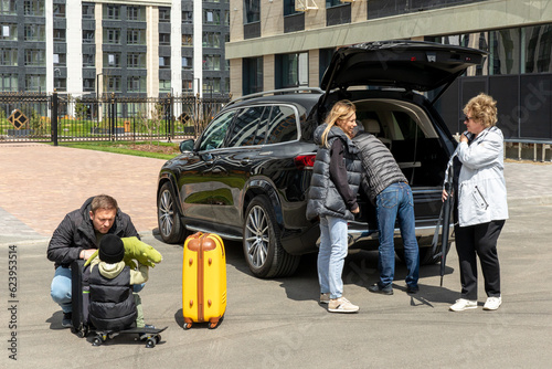 Happy multigenerational family loading baggage in trunk of car to leave on vacation with small kid, parents and grandparents. People prepaing luggage and travel bags to go on holiday journey. © Irina Mikhailichenko
