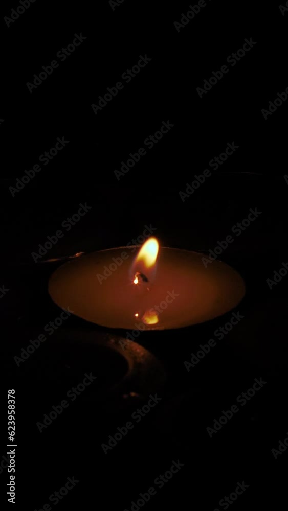 Round candle lit illuminating while it goes out leaving completely in darkness. Close up, vertical shot. Round candle lit illuminating while it goes out leaving completely in darkness. Close up, vertical shot.