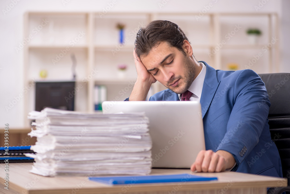 Young male employee and too much work in the office Young male employee and too much work in the office