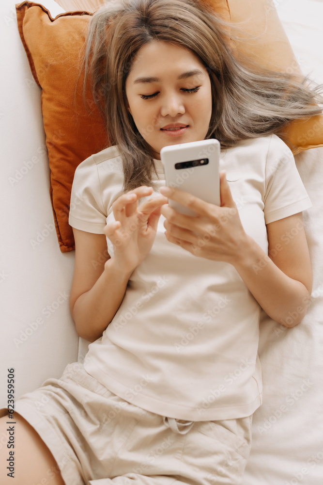 Happy asian woman rest and lie on the sofa using smartphone in the living room. Happy asian woman rest and lie on the sofa using smartphone in the living room.