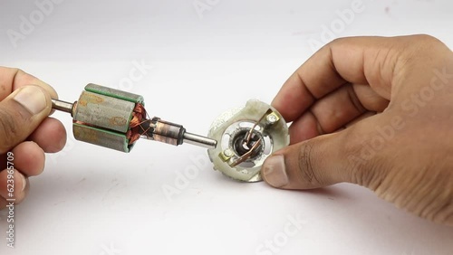 DC motor rotor with copper commutator and coil wire winding along with carbon brush held in the hand