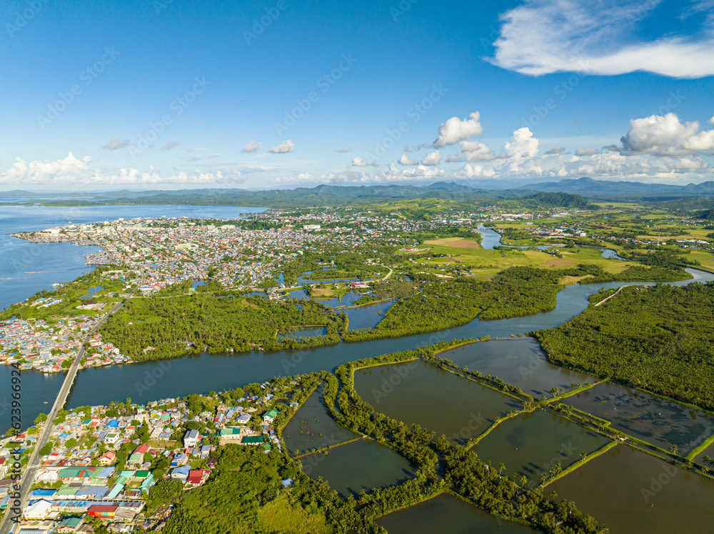 Air survey of beautiful Coastal City residential area and rainforest with river. Surigao, Philippines. Mindanao.