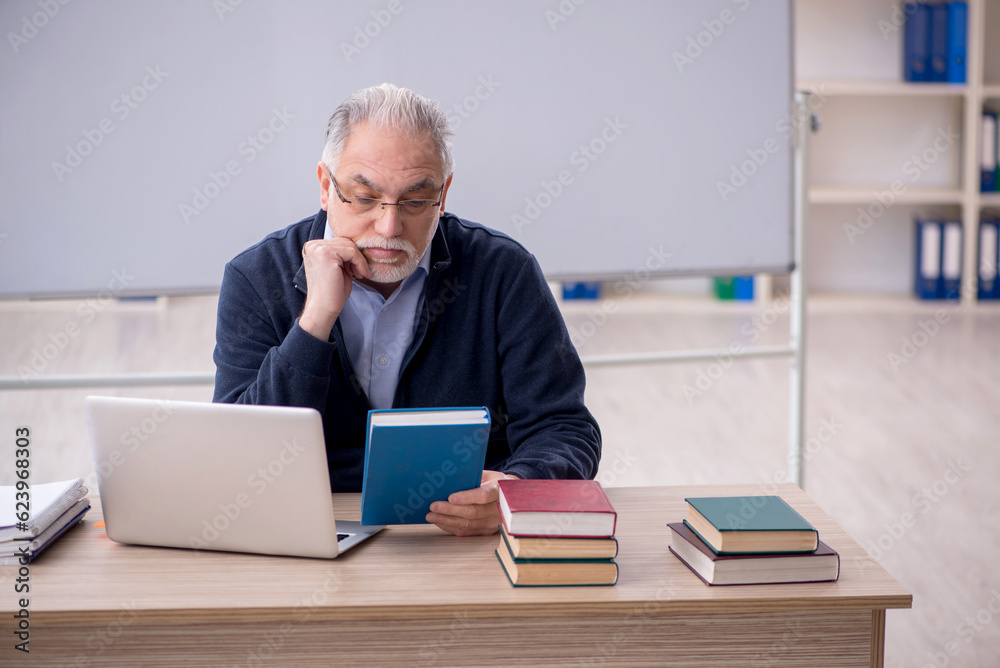 Old male teacher in the classroom Old male teacher in the classroom