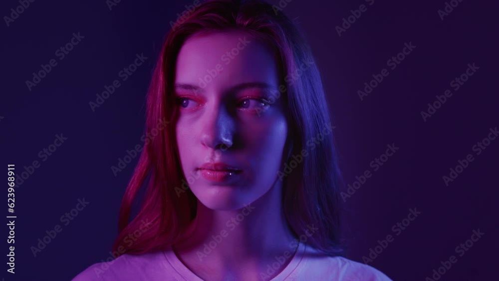 Portrait of a beautiful red-haired girl in a white T-shirt in the studio. Attractive millennial woman, neon blue pink light. Professional female model. Art make up, beauty fashion Portrait of a beautiful red-haired girl in a white T-shirt in the studio. Attractive millennial woman, neon blue pink light. Professional female model. Art make up, beauty fashion