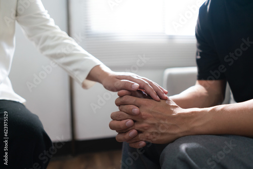 Psychologist woman touching hands to encouraging man with mental health problem in therapy center © Pichsakul