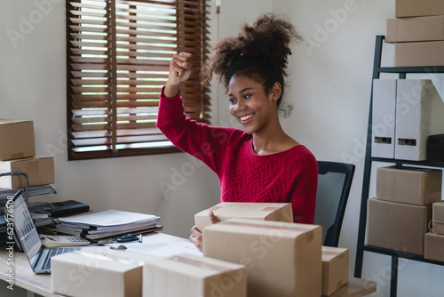 African american women raise arm to celebrate with happiness while checking online order on laptop