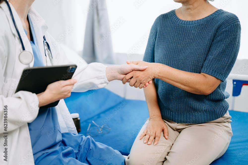 Doctor and senior female patient who lie on the bed while checking pulse, consult and explain with nurse taking note in hospital wards or clinic.. Doctor and senior female patient who lie on the bed while checking pulse, consult and explain with nurse taking note in hospital wards or clinic..