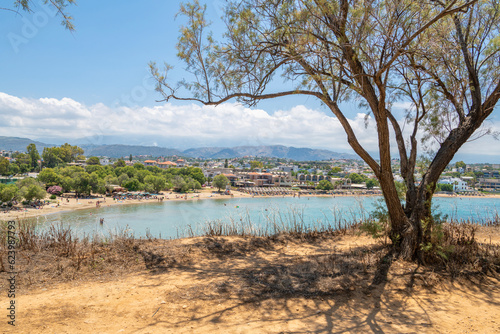 Trees on the shore of Aegean Sea and coastal view of Agioi Apostoloi village, Daratsos, Chania, Crete, Greece photo