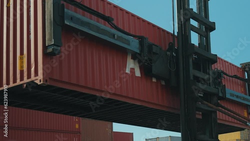 4K actual cam shooting of heavy duty forklift lifting container to place it by other stacked cargo at commercial port area stock video.