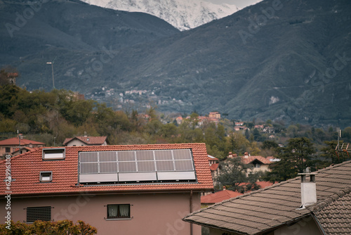 Solar panels on the roof of the modern house. Residential house cottage with blue shiny solar photo voltaic panels system on roof. Renewable ecological green energy production concept. Sustainable.