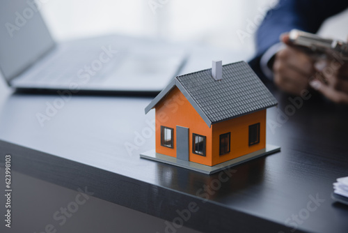 African American businesswoman with house model, Real estate agent and customer discussing for contract to buy house.