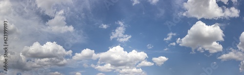 white fluffy clouds in the blue sky in sunny summer day. panoramic image.