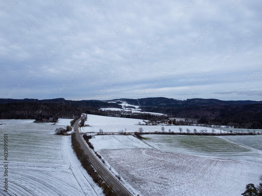 Drone shot of snowy agricultural snowy fields in Bavaria on a cloudy day