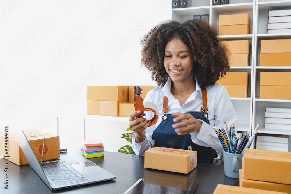 African American owner checking orders from customers sitting at desk in office, sell products online concept. African American owner checking orders from customers sitting at desk in office, sell products online concept.