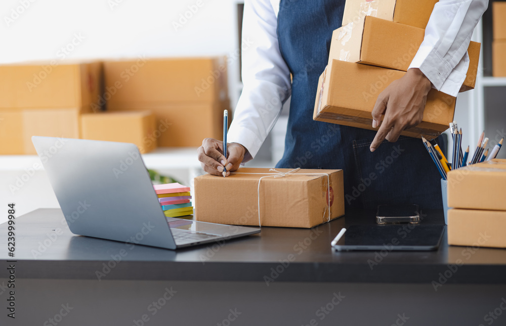 African American owner checking orders from customers sitting at desk in office, sell products online concept. African American owner checking orders from customers sitting at desk in office, sell products online concept.