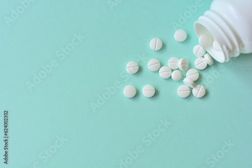 緑の背景と白い複数の錠剤と薬のボトル